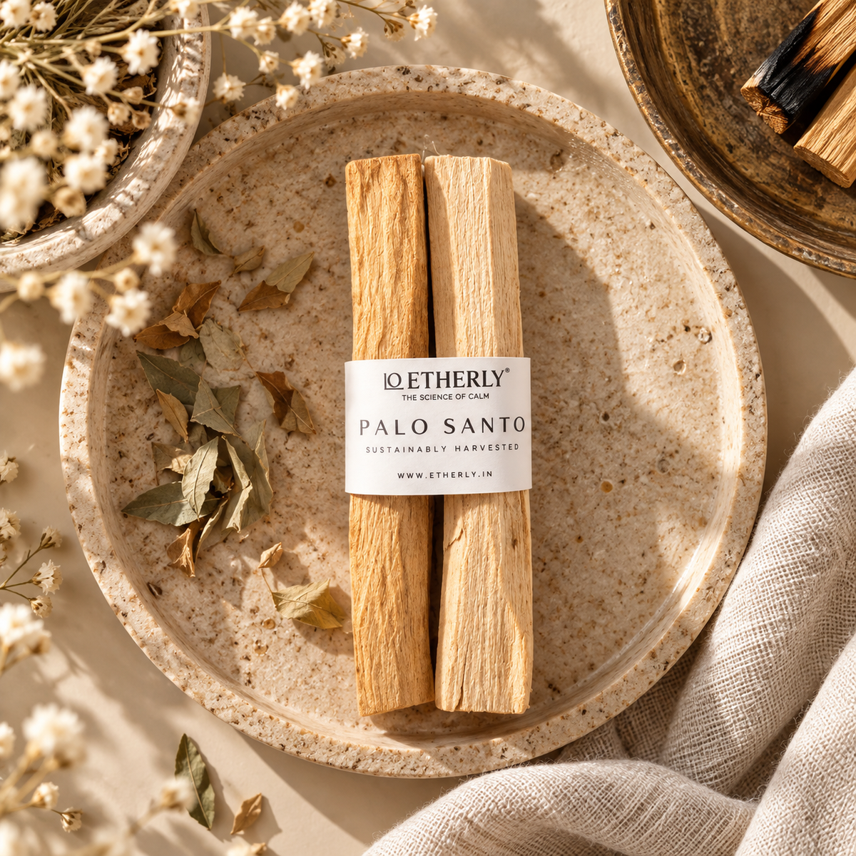 Two Palo Santo ritual wood sticks with an Etherly band on a ceramic plate